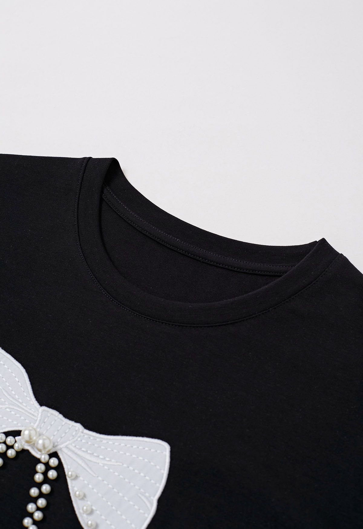 Schwarzes T-Shirt mit Schleifenmuster und Perlenverzierung